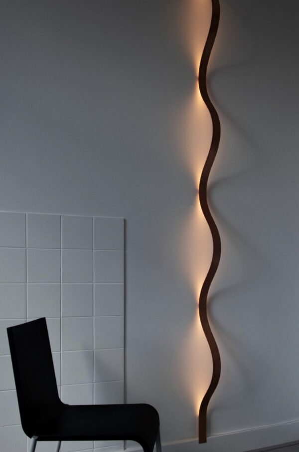 Koperen wandlamp Sine Light by David Derksen aan de muur